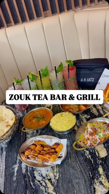 A promotional montage for Zouk Tea Bar & Grill, featuring shots of the restaurant exterior, interior, cocktail preparation, tandoor cooking, and a spread of various dishes and desserts.
