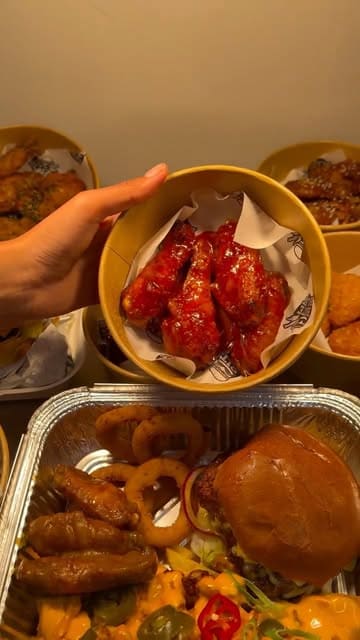 A montage of various chicken dishes including burgers, wings, and loaded fries from Bite Blast in Mile End, showcasing the saucing process and presentation of their Munch Box.