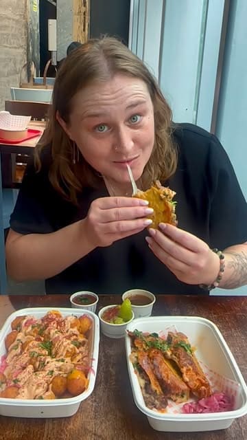 A short review video featuring a visit to Hermanos Caliente, a street food stall located within Trinity Kitchen. The creator showcases the menu, highlights specific dishes like tacos and loaded tater tots, and shares their personal recommendation.