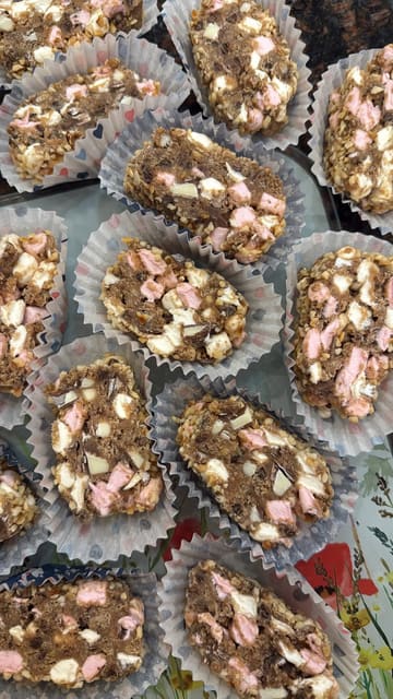 A home cooking tutorial demonstrating how to make a 'Kinder 15,' a variation of a traditional Northern Irish no-bake traybake. The video follows the creator through the process of crushing cookies, mixing ingredients, shaping the log, and chilling it.