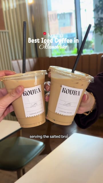 A short, energetic video showcasing a specific viral coffee drink and a dessert at Kouba in Manchester. The video focuses on the Salted Brown Butter Oat Latte served on tap and a cornflake-topped cookie, using quick cuts to maintain interest.