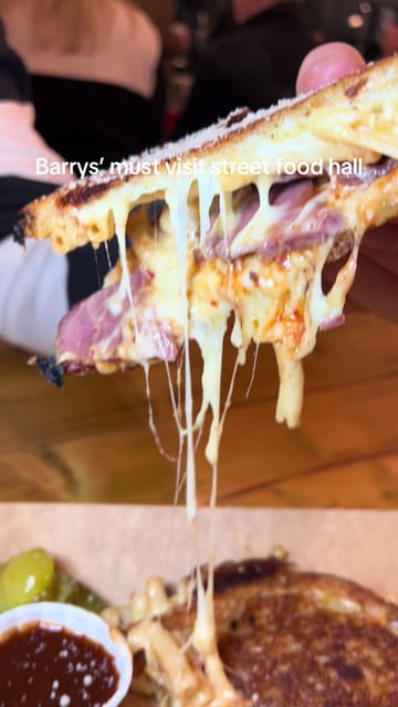 A fast-paced video showcasing a visit to Goodsheds street food hall in Barry, featuring close-ups of various dishes including a grilled cheese sandwich, sushi, pizza, and a wrap, interspersed with shots of the venue and people eating.
