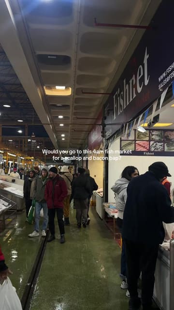A short, fast-paced video documenting a visit to Billingsgate Market in London. The creator highlights the early morning experience, the market atmosphere, and the specific food offering of a scallop and bacon bap at the market cafe.
