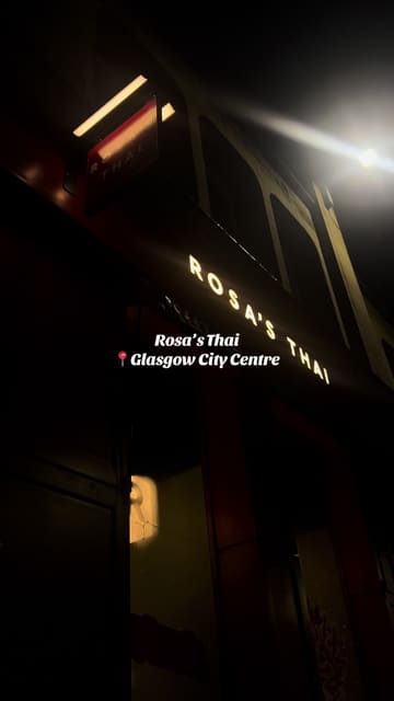 A short, handheld-style video review of a visit to Rosa's Thai in Glasgow. The creator walks through the festive menu, showing the sharing platter, main courses like red curry and pad thai, and desserts. The video includes a voiceover sharing personal thoughts on the experience and a mention of a small giveaway.