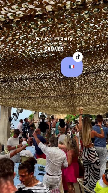 A fast-paced, energetic montage showcasing a visit to La Guérite beach club in Cannes. The video captures the journey by boat, the scenic island location, the dining experience, and the transition into a lively party atmosphere with table dancing and music.
