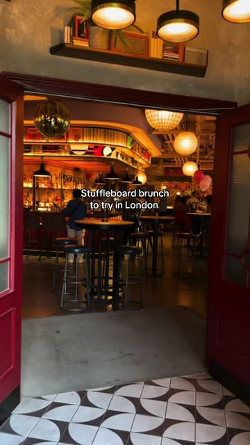 The video provides a tour of Electric Shuffle in London, highlighting the shuffleboard gaming experience, the bar atmosphere, and the food and drink offerings like pizza and wine.