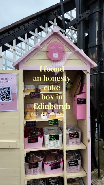 A short vlog showcasing an 'honesty cake box' located near the canal in Edinburgh, featuring a variety of homemade cakes and treats available for purchase via cash or QR code.