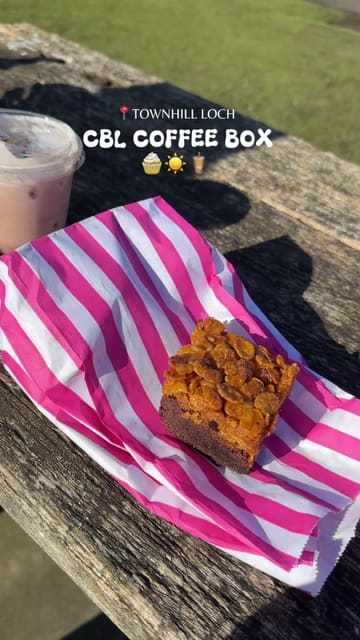 A short, aesthetic vlog showcasing a visit to CBL Coffee Box located by Townhill Loch. The video features the creator enjoying a coffee and various sweet treats like cupcakes, cookies, and brownies, set against a scenic lakeside backdrop.