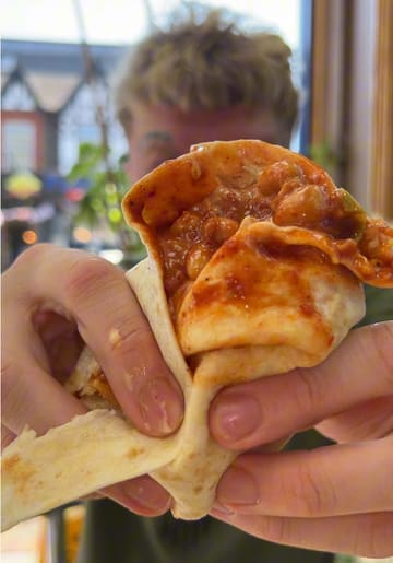 A high-energy, comedic review of a local chicken shop, focusing on a 'cursed' wrap creation involving beans and chicken, alongside wings and fries.