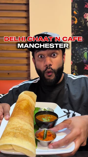 A creator reviews Delhi Chaat N Cafe in Manchester, showcasing a variety of Indian street food dishes including dosa, chicken 65, lamb chops, and chicken tikka masala. The video features the creator tasting the food, showing the menu, and providing a brief tour of the venue's interior.