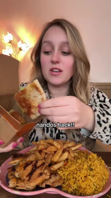 A creator demonstrates a food hack for Nando's by stuffing chicken, rice, and chips into a cheesy garlic pitta bread, followed by a taste test.
