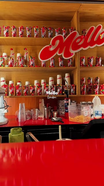 A short, polished montage of a dessert cup featuring strawberries, cream, and chocolate crumble, filmed at a Mello London kiosk. The video focuses on the product's appearance with slow, controlled shots.