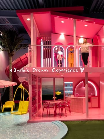 A montage of a visit to the Barbie Dream Experience in Amsterdam, featuring the daughter exploring various themed rooms, interactive exhibits, and the pink-themed cafe.