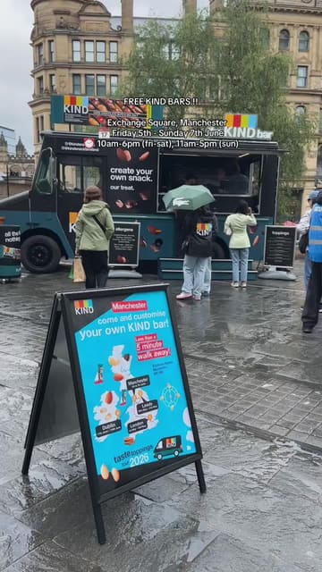 The video features a pop-up event in Manchester's Exchange Square where visitors can customize KIND bars with various toppings. The creator walks through the experience, showing the toppings station and the 'wall of kindness' where people can leave messages.
