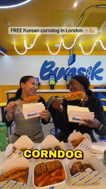A promotional video for the opening of a new Bunsik branch in Brixton, London. The creator highlights a special offer for free Korean corndogs for the first 100 customers and 50% off for the rest of the day. The video showcases the menu items, including corndogs, tteokbokki, and fried chicken, as well as the venue's interior and ordering kiosks.