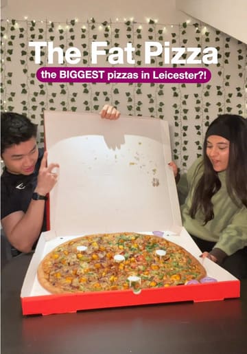 A promotional shot featuring two creators holding open a large pizza box to reveal a 24-inch pizza, designed to highlight the scale of the food. The image uses a casual, influencer-style aesthetic with text overlays to communicate the venue name and the 'biggest pizza' selling point.