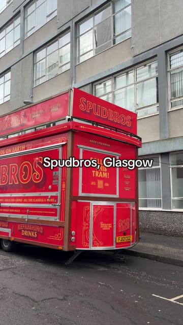 The video is a vlog-style review of the Spudbros food truck visiting Glasgow. It features the creator waiting in a long queue, showing the preparation of a loaded jacket potato with garlic chilli chicken, cheese, and 'tram sauce', followed by a taste test.