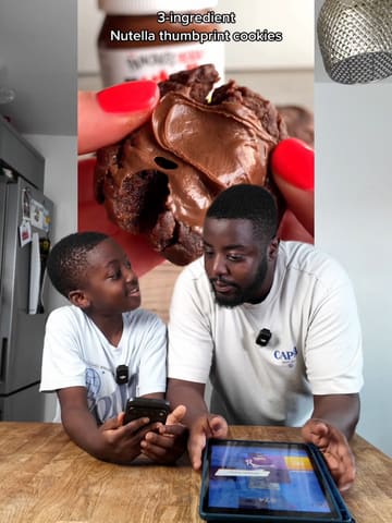 A father and son attempt a 3-ingredient Nutella cookie recipe in their home kitchen, providing a humorous and relatable cooking tutorial.