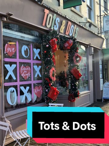 A video tour of 'Tots & Dots', a play cafe in Stony Stratford. The video showcases the cafe's interior, including the seating area, menu, and a selection of cakes and hot drinks. It also provides a walkthrough of the children's play facilities, including a soft play area, themed role-play rooms (vets, cafe, construction), and a sensory room.