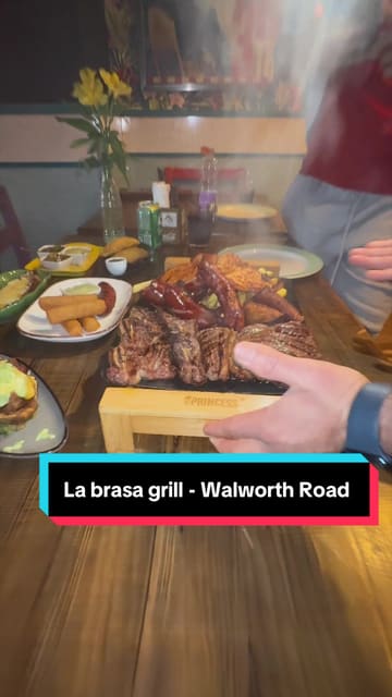 A vlog-style review of La Brasa Grill, a Latin steakhouse in London, featuring a variety of dishes including empanadas, cassava croquettes, baked plantain, and a large mixed grill platter.