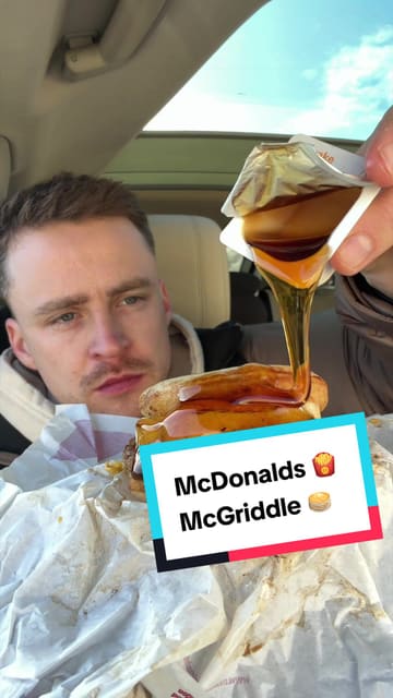 A creator reviews a McDonald's McGriddle from inside their car, providing commentary on the taste and texture of the breakfast sandwich, including a syrup pour shot.