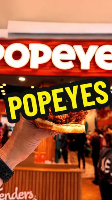 A short, energetic video showcasing a visit to a Popeyes restaurant, featuring shots of the interior and a close-up of the spicy chicken sandwich meal.