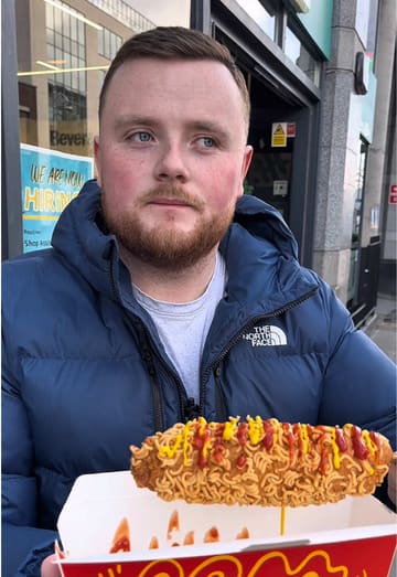 A creator reviews a ramen-coated corn dog and a blue lemon drink from Super Asia, an Asian market on Parnell Street. The video features the creator's honest, casual reaction to the unique street food item.