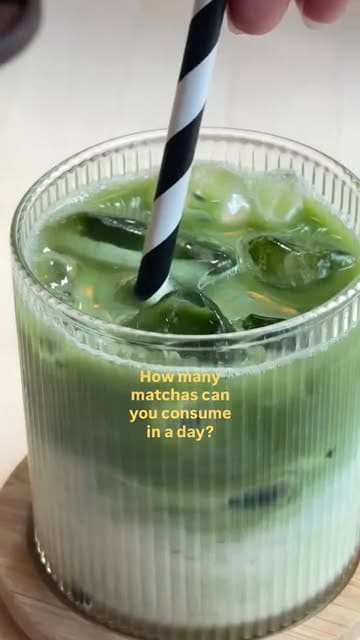 A clean, close-up shot of an iced matcha latte served in a ribbed glass with a black and white striped straw, featuring a text overlay asking about daily matcha consumption.