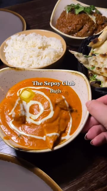 A food review vlog featuring a visit to The Sepoy Club in Bath. The creator showcases a variety of dishes including Papdi Chaat, a non-veg platter, Butter Chicken, Lamb Bhuna, Garlic Naan, and a Sizzling Brownie. The video includes shots of the restaurant interior, the menu, and the creator's reactions to the food.