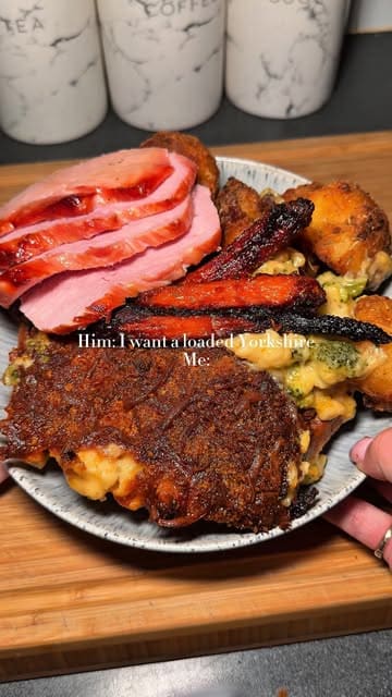A short, static video showing the assembly of a 'loaded Yorkshire pudding' featuring stuffing, roast potatoes, mac and cheese, carrots, gammon, and gravy, prepared at home.