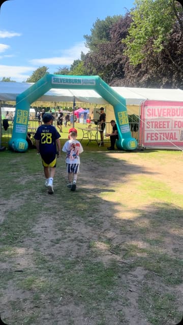 A montage video showcasing the Silverburn Street Food Festival, featuring various food stalls, live music, and children's entertainment like bouncy castles and face painting.