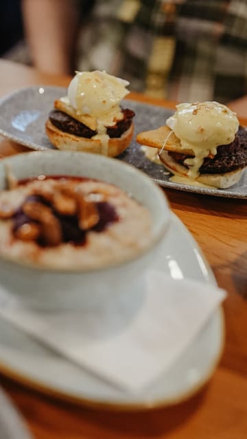 The creator visits Loudons in Edinburgh, providing a tour of the cafe and reviewing their brunch options, including smoothies, a veggie power bowl, porridge, and haggis eggs benedict.