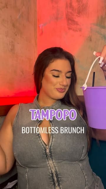 A short, energetic video review of a bottomless brunch experience at Tampopo, featuring close-ups of unique cocktails, rum buckets, and brunch dishes like a honey chicken and bacon bubble waffle and a crispy avocado stack.