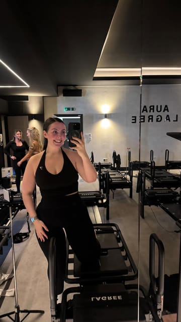 A creator reviews her first Lagree fitness class at Aura Lagree, explaining the workout style and sharing her positive experience. The video features the creator demonstrating the exercises on the equipment and providing commentary on the intensity and benefits of the class.