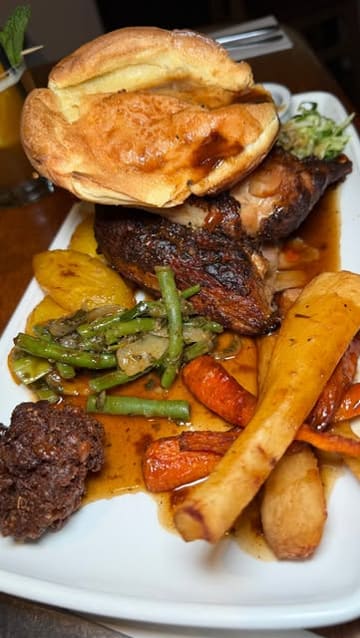 A vlog-style review of a Caribbean restaurant called Cottons, highlighting their 'Reggae Sundays' event. The video features shots of the menu, various dishes including a Sunday roast, mac and cheese, and tempura, as well as the live music entertainment and the restaurant's interior.