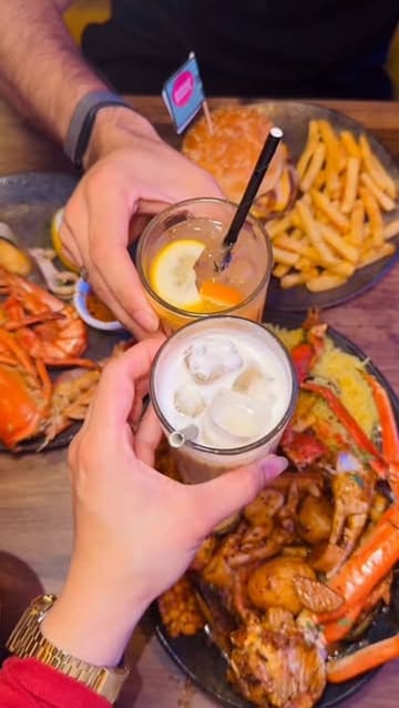 A short, engaging reel showcasing a seafood boil and burger at Shrimp Shack Manchester, featuring close-up shots of the food and drinks.