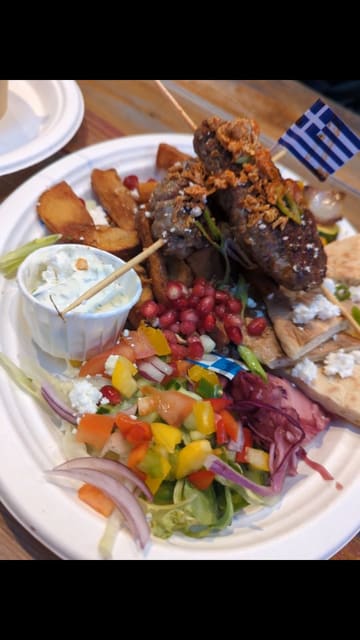 A short promotional video for The Gyros Place located in an indoor market, featuring shots of the exterior, the menu, and close-ups of various Greek dishes including lamb kofte, gyros, and loaded fries.