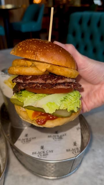 A promotional video for Black Cat Club, showcasing the venue's atmosphere, competitive socialising activities like darts and shuffleboard, and their food and drink menu, including burgers and cocktails.