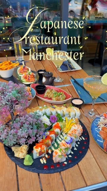 A short, visually-focused reel showcasing a variety of Japanese dishes including sushi, bao buns, and cocktails at Zumuku Sushi in Manchester. The video uses a mix of static and smooth handheld shots to highlight the presentation of the food, including a dry ice effect on the sushi platter, and provides a brief look at the restaurant's interior.