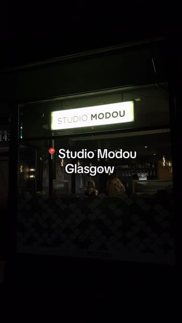 A personal review of Studio Modou in Glasgow, showcasing a three-course set menu priced at £25 per person. The video features the restaurant's interior, cocktails, and various dishes including a scotch egg, mushroom velouté, duck, and chocolate fondant.