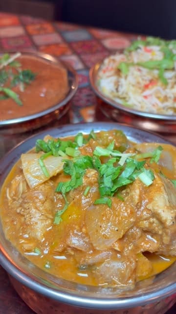 A short, engaging montage showcasing the food and atmosphere at Chaupal, an Indian restaurant in Leeds. The video features close-up shots of various dishes, including a mixed grill, chicken jalfrezi, butter chicken, and garlic naan, accompanied by text overlays describing the experience.
