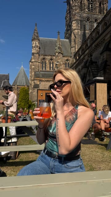 A short, engaging video showcasing The West End Garden in Edinburgh, an outdoor pop-up venue located on the grounds of St Mary's Cathedral. The video features the creator enjoying a spritz and pizza, highlighting the relaxed atmosphere, menu options, and the scenic location.