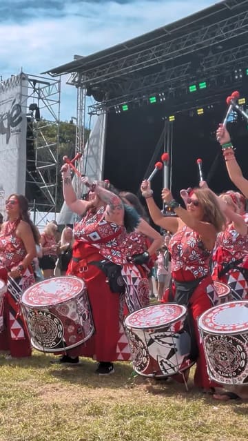 A recap video of the Africa Oyé festival in Sefton Park, Liverpool. The video features live drumming performances, crowd shots, a henna artist, various market stalls selling jewelry and accessories, and street food including a jerk chicken wrap and fried dough.