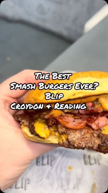 A review of Blip Burgers, featuring a variety of their menu items including smash burgers, chicken burgers, loaded fries, onion rings, a milkshake, and banana pudding. The video provides a look at the venue's interior and menu board.