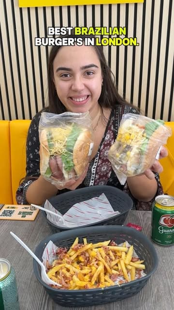 A creator reviews Brazilian burgers at Cozinha do Humberto in London, showcasing various burger options, fries, snacks, and a drink.