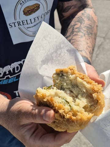 A casual, handheld video review of a chip cob from Chesters Fish Bar in Chesterfield. The creator discusses the regional naming conventions of the dish while showing the food item and the exterior of the shop.