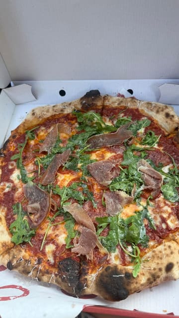 A creator reviews two pizzas from Orto, a pizza venue, while sitting in his car. He describes the toppings, the crust, and the dips, providing an enthusiastic and personal recommendation for the food.