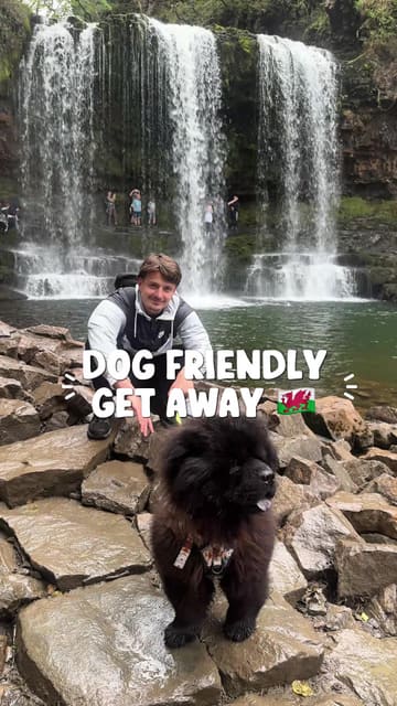A couple documents their dog-friendly trip to Wales, featuring visits to waterfalls, a stay in a hut with a hot tub, and a meal at a burger restaurant called Hills.