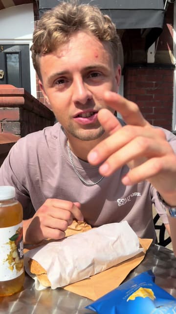 A creator reviews sandwiches from CJ's Sandwich Shop in Whalley, showcasing a bacon and sausage butty and a salmon baton while sitting outside the venue.