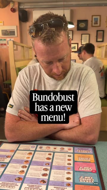A couple visits Bundobust to review their new menu, showcasing a wide variety of vegetarian Indian street food dishes and craft beer. The video features close-ups of the food, the menu, and the creators enjoying the meal in a casual, friendly atmosphere.